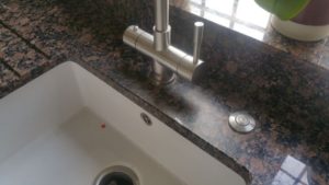 Limescale around a kitchen tap on a granite surface